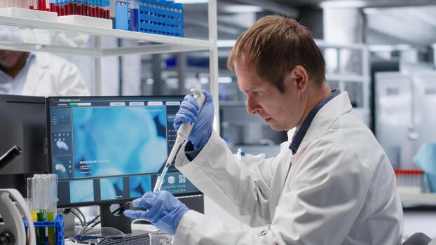 Male scientist handles pipette with droplet over jar during procedure in the lab. Mixture preparation supporting genetics research, nanotechnology and solutions through analytical methods. photo