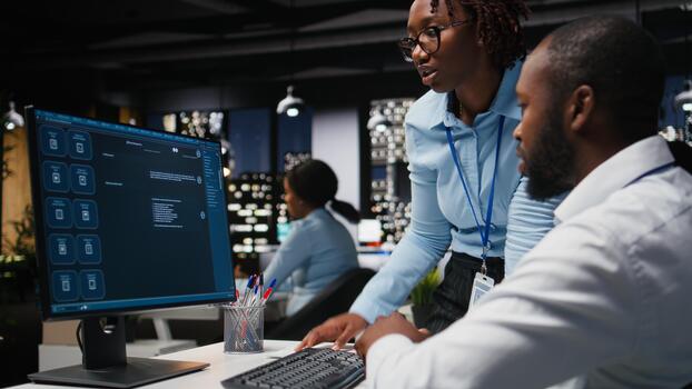 Two black workers interacting with a virtual assistant on computer at desk, responses and smart automation to improve online communication. Data driven AI solutions. photo