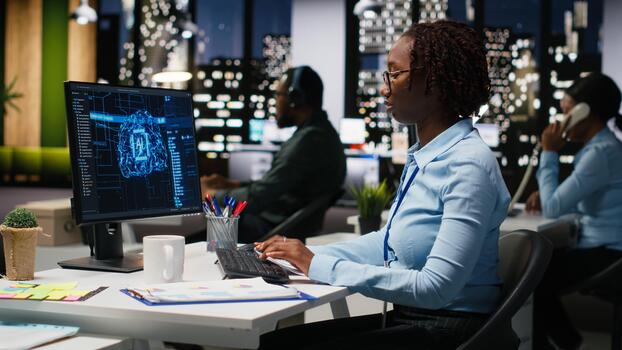 African american woman reviewing KPI metrics with artificial intelligence on pc monitor, working with AI neural networks for deep learning. Emphasizing innovation and optimization. photo