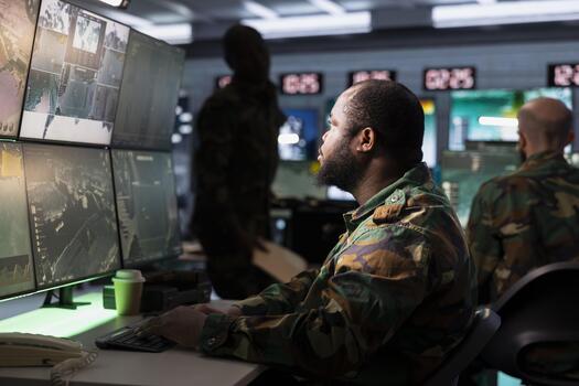 Military officer conducts tactical reconnaissance in command post, utilizing devices for data analysis. Army specialist uses satellite technology to look at aerial map, pinpointing enemy targets photo