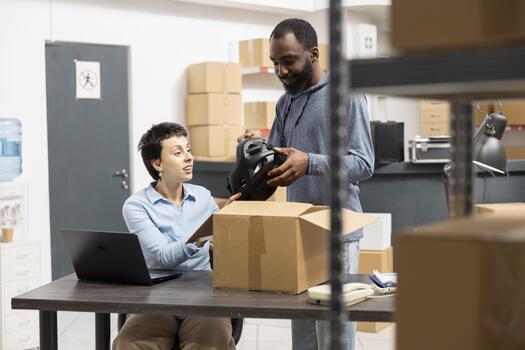 Team of colleagues ensuring custom orders processing and hand packing goods, working on import export or distribution with multiple products. Overseeing product handling in the supply room. photo