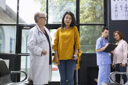 Doctor guiding patient with locomotor disability while using crutches for physical support in healthcare setting. Recovery journey includes walking exercises and professional advice. photo