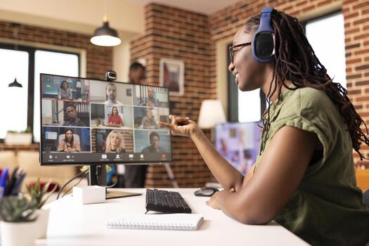 Black female manager uses headphones and computer in communicating with colleagues during virtual meeting. Self employed woman virtually presenting startup project with potential clients on call photo