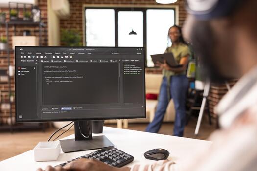 African american software developer typing at home desk, refining code and solving bugs on computer. Male remote worker focuses on improving application performance in home workstation. photo