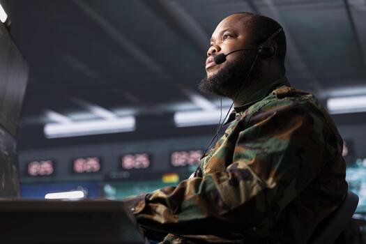 Army telecommunication systems agent using radio and satellite equipment, providing combat support using headset mic. Soldier managing communications networks, talking in microphone photo