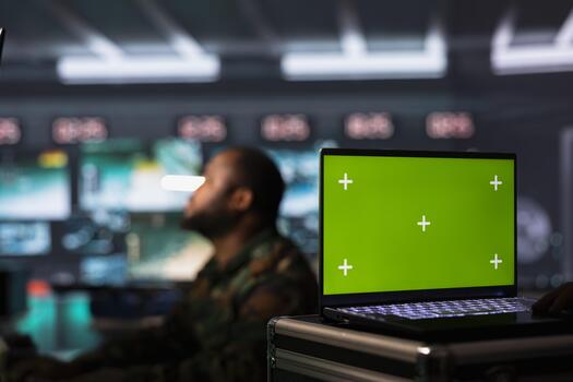 Soldier in base of operations housing missile defense system, intercepting ballistic rockets using green screen laptop. Intelligence service professional using radar system on chroma key notebook photo