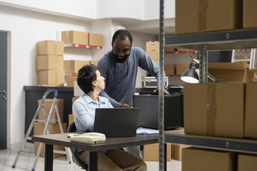 Multiethnic staff collaborates in order processing storage room, surrounded by packages and technology systems in a modern inventory depot designed for small scale distribution services. photo