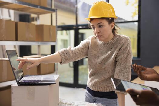 Staff members ensuring accurate order processing on a laptop, checking stock inventory in a small scale depot. Supporting e-business services with retail shipment and in house quality control. photo