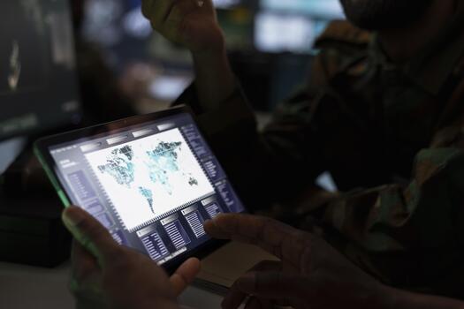 Military officer using tablet device to deploy electronic warfare tools to disrupt enemy communication systems. Soldier operating on high tech infrastructure weapons, close up photo