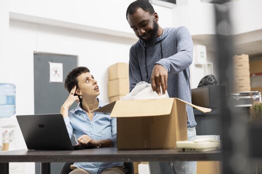 Diverse workers checking digital inventory system for delivery logistics, using laptop and coordinating shipment services in a warehouse setup. Local brand operations and e commerce growth. photo