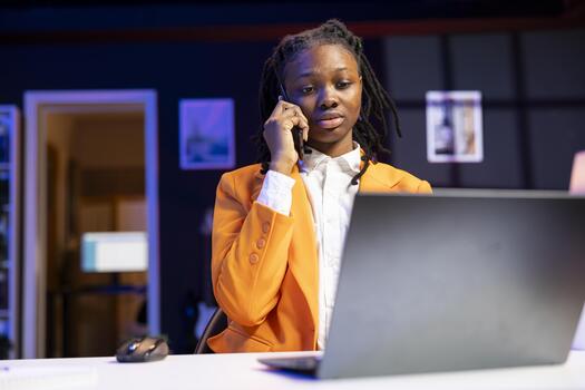 Student at desk in phone call with teacher, requesting help to do homework, browsing internet on laptop. African american person doing telephone call and reading articles on laptop for school tasks photo