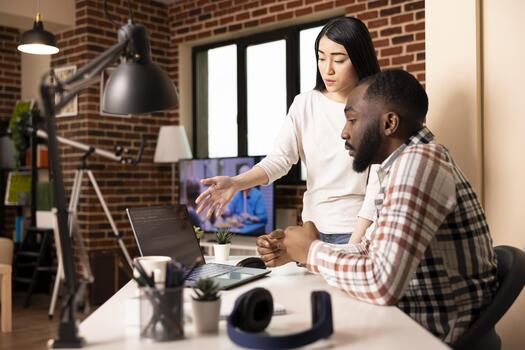 apoyo Novia que se discute software en ordenador portátil con enfocado masculino desarrollador a hogar oficina escritorio. multiétnico Pareja trabajando remotamente juntos y lluvia de ideas en aplicación desarrollo para tecnología compañía. foto