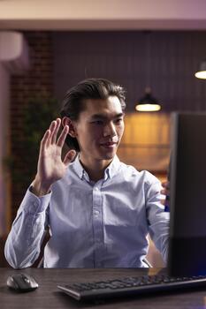 enfocado hombre gestos Hola a móvil teléfono durante llamar, utilizando tecnología a permanecer productivo. empresario gestiona virtual comunicación con clientela y colegas, trabajando remotamente desde hogar. foto