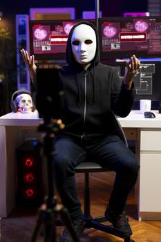 Hacker hidden in underground lair sending ultimatum to foreign governments, hacking systems. Masked rogue programmer threatening retaliation against military target if his conditions are not met photo