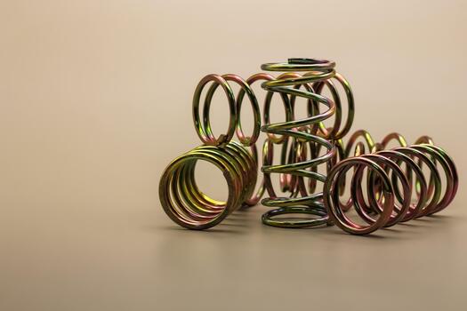 Assortment of metallic coil springs displaying a vibrant iridescent sheen on a neutral surface, representing essential mechanical components for diverse industrial and technological applications photo