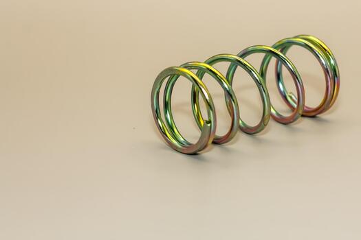 Close-up of a metallic spring, showcasing its coiled structure and reflective surface on a neutral background photo
