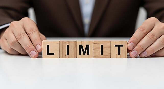 Business professional arranging wooden blocks spelling LIMIT on a white table symbolizing boundaries constraints and the importance of setting limitations for success and achieving goals in a corporat photo