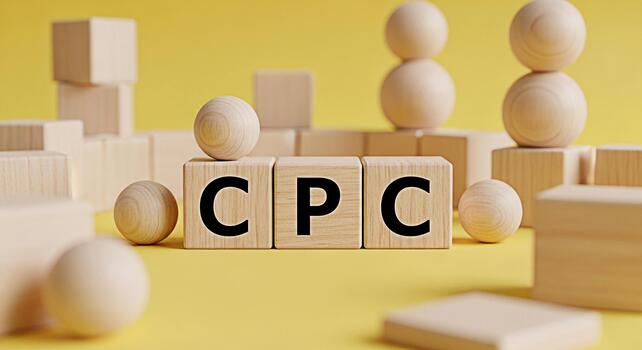 Wooden blocks displaying CPC on a yellow surface surrounded by wooden spheres and cubes symbolizing cost per click and pay per click advertising in a simple and minimalist setting photo