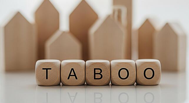 Wooden dice spelling TABOO in a minimalist setting with blurred house shapes in the background representing forbidden topics and creating a sense of mystery and intrigue perfect for social commentary photo