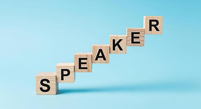 Wooden blocks spelling SPEAKER arranged in a staircase formation against a light blue background symbolizing growth and communication skills conveying a message of progress and development photo
