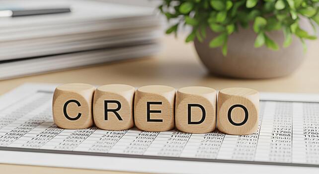 Wooden blocks spelling CREDO resting on a financial spreadsheet in a bright office symbolizing core beliefs and principles in business and personal life fostering trust and ethical decisionmaking photo