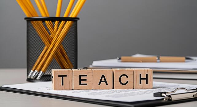 Wooden blocks spelling TEACH on a clipboard in a classroom setting symbolizing education and learning with pencils and a pen in the background creating a focused and inspiring atmosphere for educators photo