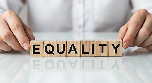 Hands arranging wooden blocks spelling EQUALITY on a reflective white surface symbolizing fairness and justice in a bright hopeful environment promoting a message of equal rights and opportunities photo