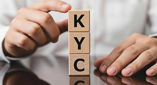 Closeup of a person arranging wooden blocks with the letters KYC on a reflective surface representing Know Your Customer compliance and regulatory requirements in a business setting photo