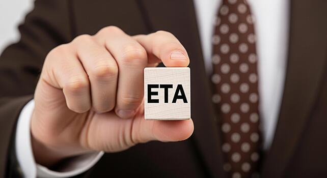 Professional businessman in a suit holding a wooden block with the letters ETA in a neutral setting representing estimated time of arrival project management and deadline communication with a sense of photo