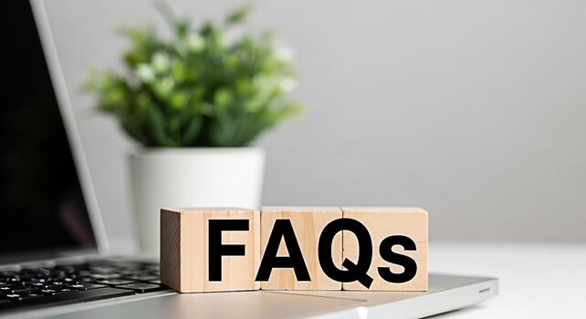 Wooden blocks displaying FAQs on a laptop in a bright modern office setting symbolizing readily available information and customer support for online queries and common questions photo