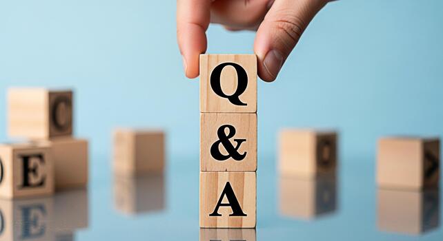 Hand stacking wooden blocks spelling QA on a reflective surface against a blue background representing questions and answers knowledge learning and information exchange in a clear and concise manner photo