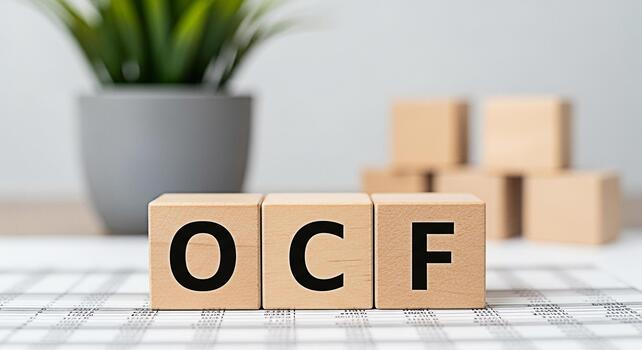 Wooden blocks spelling OCF on a financial spreadsheet in a bright office setting representing cash flow from operations and financial analysis for business growth and investment decisions photo
