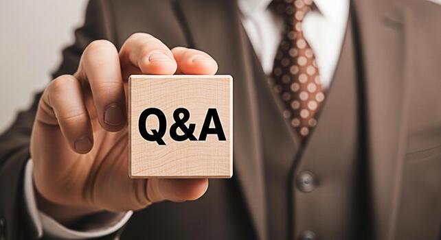 Professional businessman in a suit holding a wooden block with QA text in a corporate environment representing questions and answers knowledge sharing and business communication photo