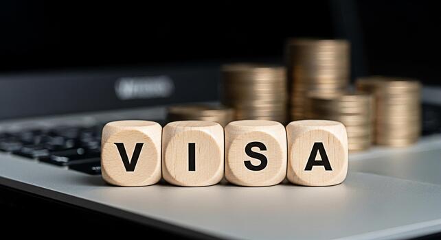Wooden blocks spelling VISA sitting on a laptop with stacks of coins in the background representing financial transactions and global payments with a focus on convenience and security photo