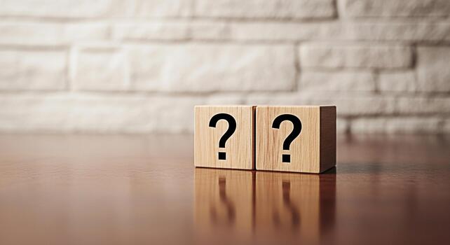Two wooden blocks displaying question marks on a polished wooden surface against a textured brick wall symbolizing uncertainty and the search for answers in a clean minimalist setting photo
