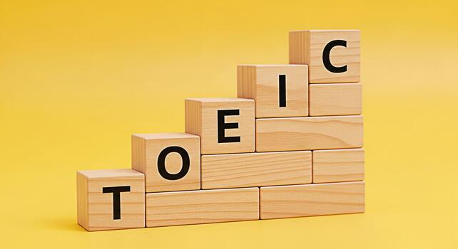 TOEIC letters on wooden blocks stacked in a step formation against a bright yellow background symbolizing learning progress and success in English language proficiency testing photo