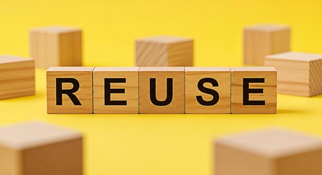 Wooden blocks spelling REUSE in a bright yellow studio setting promoting environmental awareness and sustainable living emphasizing the importance of reducing waste and conserving resources for a gree photo