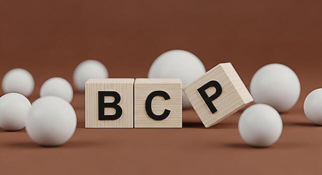 Wooden blocks spelling BCP on a brown surface surrounded by white spheres representing Business Continuity Planning and disaster recovery in a minimalist and conceptual setting photo