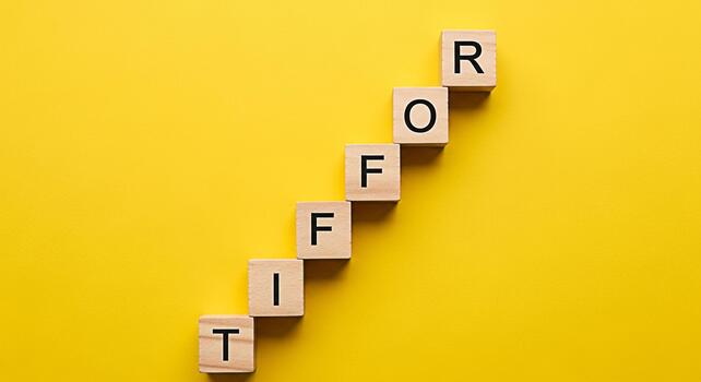 Wooden blocks spelling TIFFOR arranged diagonally on a bright yellow background symbolizing a spelling concept and creating a playful educational mood ideal for learning and creative projects photo