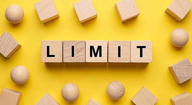 Wooden blocks spelling LIMIT on a vibrant yellow background surrounded by scattered wooden shapes representing boundaries and constraints in a playful and educational setting photo