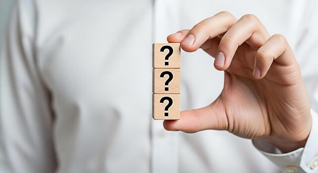 Hand holding wooden blocks with question marks in a bright studio setting symbolizing uncertainty problemsolving and the search for answers in business and personal life photo