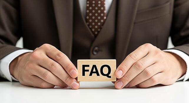 Professional businessman in a suit holding a wooden block with the text FAQ on a white desk representing frequently asked questions and providing helpful information with a confident and trustworthy d photo