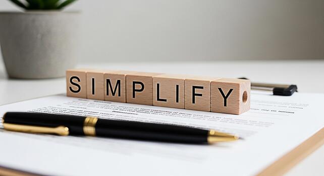 Wooden blocks spelling SIMPLIFY resting on a document in a bright minimalist office setting representing the concept of streamlining processes and achieving clarity in business and personal life photo