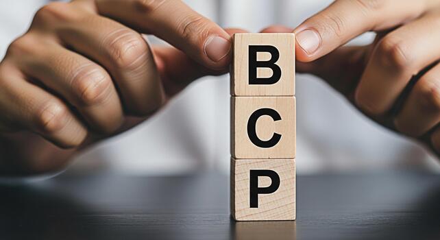 Hands arranging wooden blocks with the letters BCP on a dark table representing Business Continuity Planning symbolizing preparedness and strategic foresight in a corporate environment photo