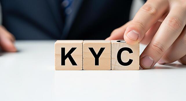 Hand arranging wooden blocks spelling KYC on a white table representing Know Your Customer compliance and identity verification in a clean professional setting conveying trust and security photo