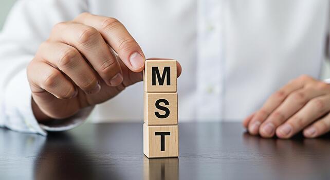Hand stacking wooden blocks with letters MST on a dark table representing Master of Science and Technology degrees symbolizing education academic achievement and career advancement in a professional s photo