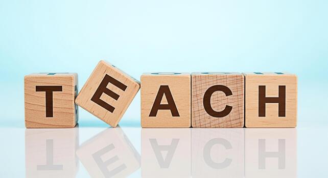 Wooden blocks spelling TEACH on a reflective surface against a light blue background symbolizing education learning and the importance of teachers in a bright and optimistic setting photo