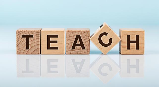 Wooden blocks spelling TEACH on a reflective surface against a light blue background symbolizing education and the importance of learning creating a positive and inspiring atmosphere for students and photo