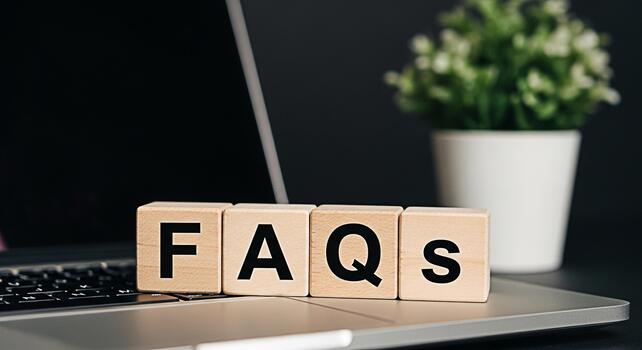 Wooden blocks spelling FAQs resting on a laptop keyboard in a modern office setting symbolizing information access and customer support with a clean and professional aesthetic photo