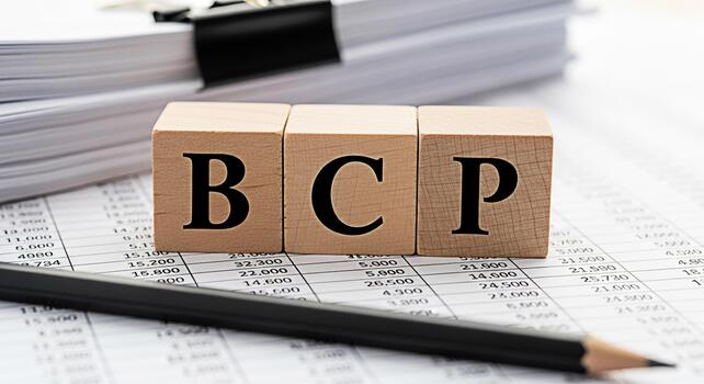 Wooden blocks spelling BCP resting on financial documents in a bright office setting symbolizing business continuity planning and risk management for a secure and resilient future photo
